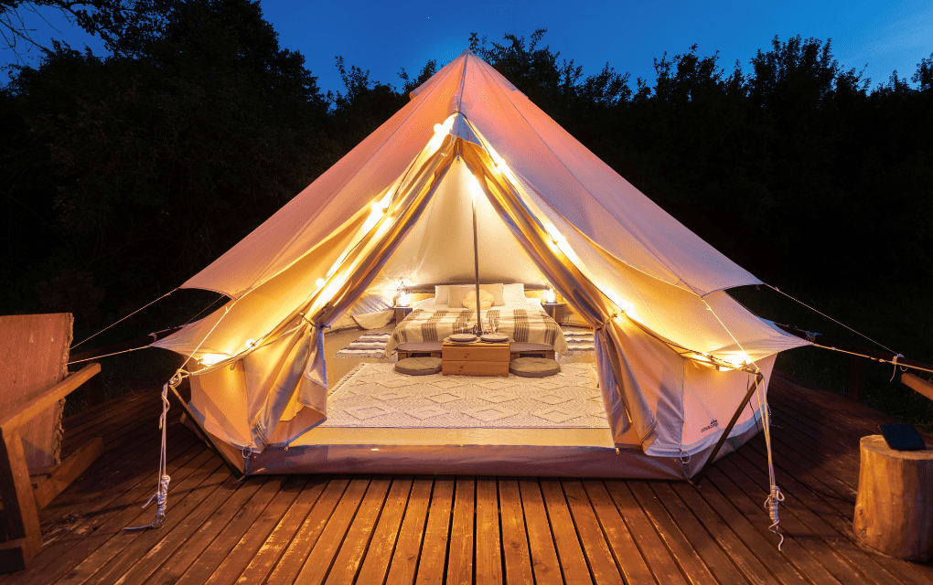A tent with lights and a bed for glamping.