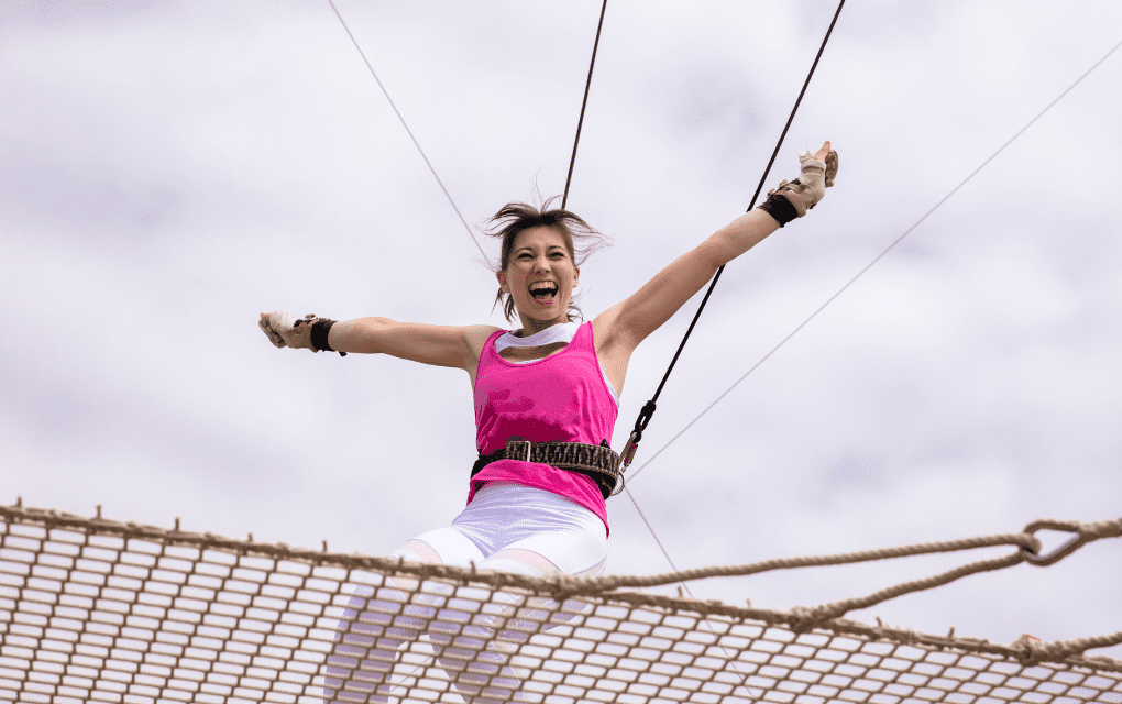 A woman is jumping up from a net during a trapeze class,
